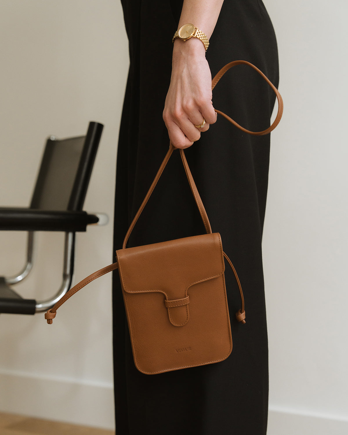 Person holding a brown leather handbag in an indoor setting