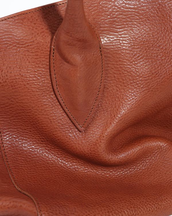 Close-up of a brown leather handbag with visible texture and stitching.