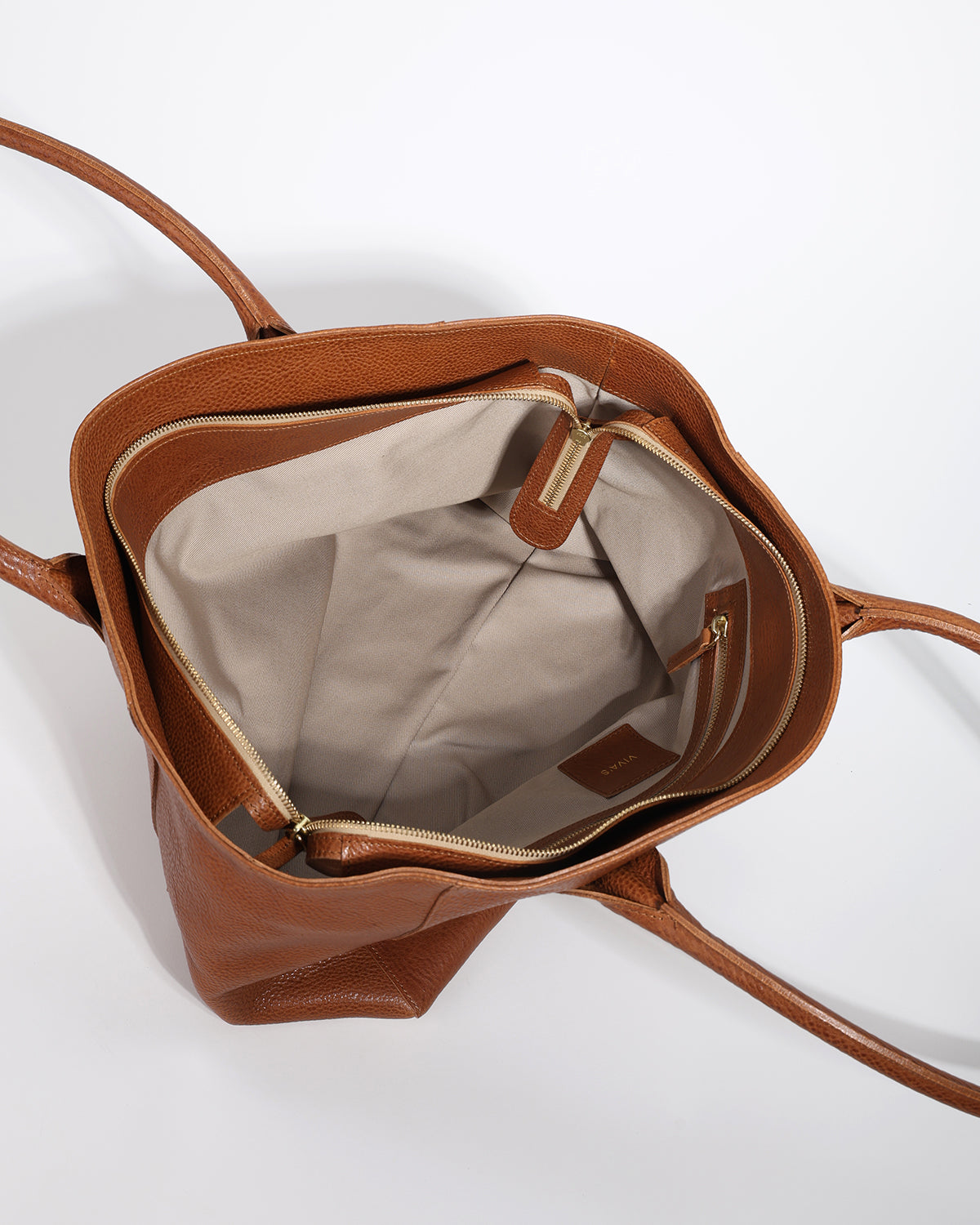 Brown leather handbag with beige interior on a white background