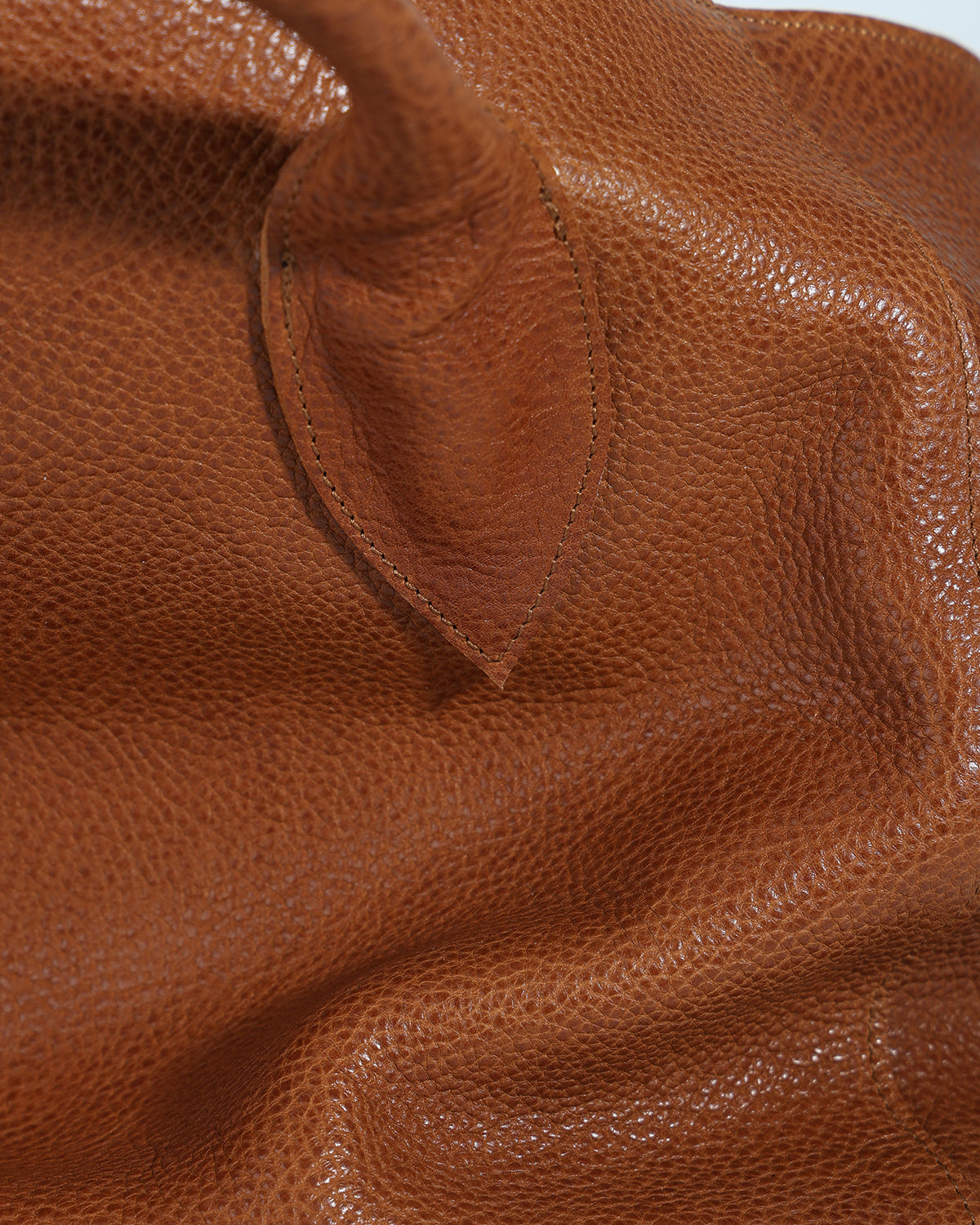 Close-up of a brown leather bag with visible texture and stitching.