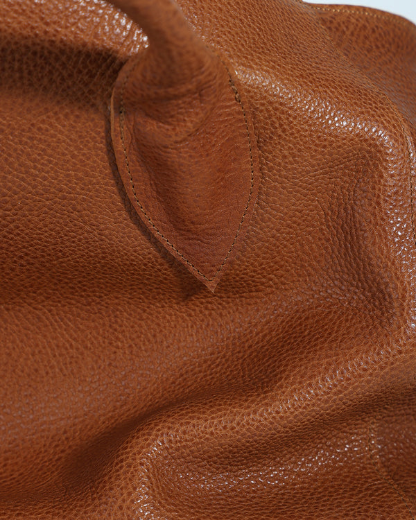 Close-up of a brown leather bag with visible texture and stitching.